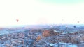 Hot air balloons flying over the caves covered by snow in Cappadocia