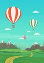 Hot air balloons flying over green meadows with dirt road and trees, snowy mountains with bright blue sky and clouds. Royalty Free Stock Photo