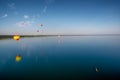 Hot air balloons flying over lake.