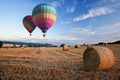 Hot air balloons over hay bales sunset landscape Royalty Free Stock Photo