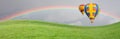 Hot Air Balloons Drift Above Grass Field with Rainbow in the Sky Royalty Free Stock Photo