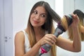 Hot air hair brush. Close-up of young woman using round brush hair dryer to style hair. Pretty girl using electric blowout brush Royalty Free Stock Photo