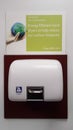 Hot air hand dryer on a wall with an evironmentally friendly sign above informing customers about energy efficiency