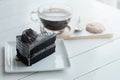 Hot americano black coffee and A piece of charcoal cake on white wooden table.