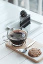 Hot americano black coffee and A piece of charcoal cake on white wooden table.