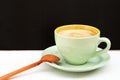 Hot Americano coffee with creamy foam on top. Put it in a green glass and saucer. With an orange spoon on the side of a white Royalty Free Stock Photo