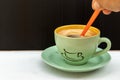 Hot Americano coffee with creamy foam on top. Put it in a green glass and saucer. With an orange spoon on the side of a white Royalty Free Stock Photo