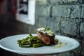 Hot appetizing tasty pork in mushroom sour cream sauce with baked green beans on a white plate in a bar on the background of a