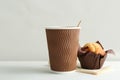 Hot aromatic coffee in paper cup and tasty muffin