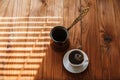 Hot aromatic coffee in a white porcelain cup on a saucer on a wooden table in the morning.