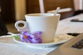 A cup of coffee on a table, indoors, close-up of a hot beverage and tiny purple flowers  - saffron, crocus sativus Royalty Free Stock Photo