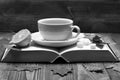 Hot beverage with sugar cubes placed on open book on wooden background. Warm drink and home relax concept. Tea cup on Royalty Free Stock Photo