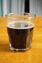 Hot black coffee in a clear glass is placed on yellow wooden table Royalty Free Stock Photo