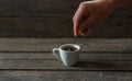 Hot black coffee or espresso in a white ceramic cup on a background of wooden texture stirs a female hand with a spoon Royalty Free Stock Photo