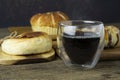 Hot black coffee is placed on the wooden table, there is bread in the background Royalty Free Stock Photo