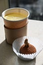 Hot black tea with lemon in a disposable cardboard cup and chocolate truffle cake sprinkled with cocoa and decorated with walnuts.