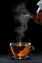 hot black tea pouring from teapot into glass cup with lemon Royalty Free Stock Photo