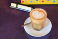 Hot Brown Caffe Latte coffee decorated with heart froth art on steamed milk foam in glass on rustic wooden table background. Royalty Free Stock Photo