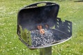 An hot burning empty charcoal barbecue with open fire. Preparing delicious outdoor barbecue on a green meadow with daisies on a Royalty Free Stock Photo