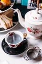 Hot Butterfly Pea Blueberry Tea served by pouring from mug through stainless steel tea strainer infuser in porcelain vintage cup Royalty Free Stock Photo