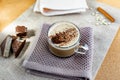 Hot cappuccino with chocolate chips on top of the foam, a cinnamon stick, Golden sugar beads and a sweet waffle next to it