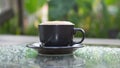 Hot cappuccino coffee cup on grass table in garden with dewdrop Royalty Free Stock Photo