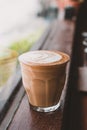 Hot cappuccino coffee cup with latte art milk foam on wood table near window in sunlight at cafe restaurant.Leisure lifestyle.food Royalty Free Stock Photo