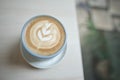 Hot cappuccino coffee cup with tree shape latte art milk foam on wood table near window in garden at cafe restaurant Royalty Free Stock Photo