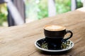 Hot cappuccino coffee cup with tree shape latte art milk foam on wood table near window in garden in sunlight at cafe restaurant. Royalty Free Stock Photo