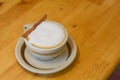 Hot cappuccino in a white cup with cinnamon bark on wooden table Royalty Free Stock Photo