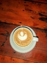 Hot capuccino coffee on white mug in wooden table