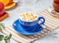 Hot caramel macchiato in blue cup on mat with grey background breakfast drink Royalty Free Stock Photo