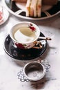 Hot Chamomile Tea served in porcelain vintage cup with stainless steel tea strainer infuser on marble top table Royalty Free Stock Photo