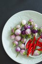 Hot chili peppers and purple thai eggplants on a green plates on a black background.