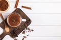 Hot chocolate in the cup, cocoa beans and powder on the white wooden table