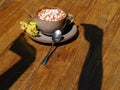 Hot chocolate in a cup on a table background. A sweet milk coffee with marshmallows, flowers, and a shadow of hands. Royalty Free Stock Photo