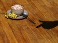 Hot chocolate in a cup on a wooden table background. A sweet cappuccino with marshmallows next to a shadow of a hand. Royalty Free Stock Photo