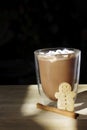 hot chocolate glass with cute smiling gingerbread cookie man with cinnamon stick and copy space