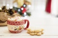 Hot chocolate with marshmallow candies. Christmas cookies shaped in snowflakes, golden cones and christmass tree lights. White wo