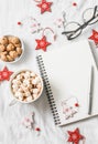 Hot chocolate with marshmallows and cinnamon, clean blank notepad, christmas decorations on a light background. Christmas inspirat