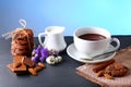 Hot chocolate and milk, cup of cocoa, chocolate cookies, almonds, flowers on a shale board on bright blue background, place to cop Royalty Free Stock Photo
