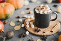 Hot chocolate with mini marshmallows served in a black mug with cocoa powder, cinnamon sticks, star anise, pumpkins and yellow lea Royalty Free Stock Photo