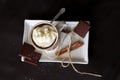 Hot chocolate in a mug with handle, spices and chocolate pieces on a white plate on a black background from above Royalty Free Stock Photo