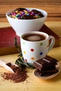 Hot chocolate in spotted cup with sweets in bowl