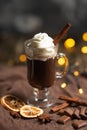 Hot chocolate in a transparent mug with whipped cream and cinnamon sticks, spices, nuts and cocoa powder on a rustic wooden backgr Royalty Free Stock Photo