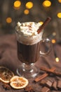 Hot chocolate in a transparent mug with whipped cream and cinnamon sticks, spices, nuts and cocoa powder on a rustic wooden backgr Royalty Free Stock Photo