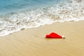Hot Christmas. Warm New Year background, winter pattern. Santa Hat on the sand.