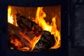 Hot coals in the fire, tongues of flame rise over firewood.