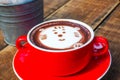 Hot cocoa and face cat milk foam in the red cup on wood background Royalty Free Stock Photo