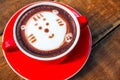 Hot cocoa and face cat milk foam in the red cup on wood background Royalty Free Stock Photo